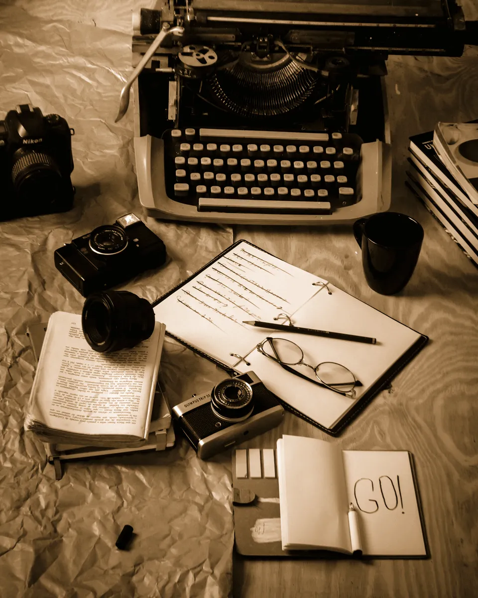 Bureau d'écrivain avec machine à écrire, carnet et appareils photo anciens.