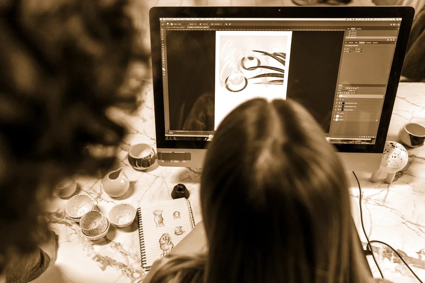 Une graphiste travaille une composition sur écran, entourée de matériel d'atelier.